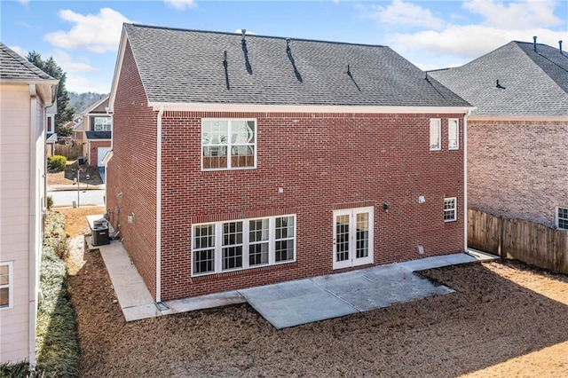 back of house with central AC, brick siding, fence, roof with shingles, and a patio area