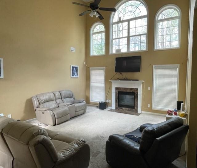 living room with a high ceiling, ceiling fan, carpet floors, and a fireplace