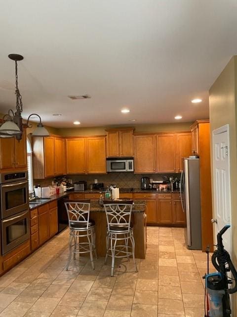 kitchen featuring stainless steel appliances, decorative light fixtures, a kitchen island, light tile floors, and a breakfast bar