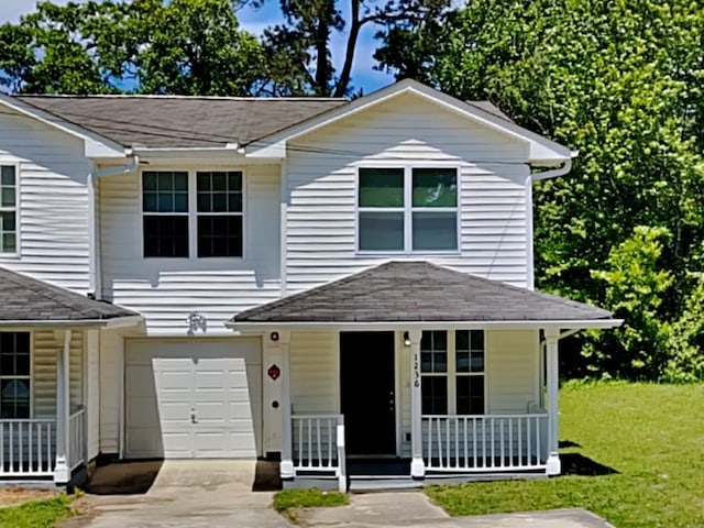 1236 Pinedale Cir NW, Conyers, GA 30012 - view of front of house with covered porch, concrete driveway, an attached garage, a front lawn, and roof with shingles