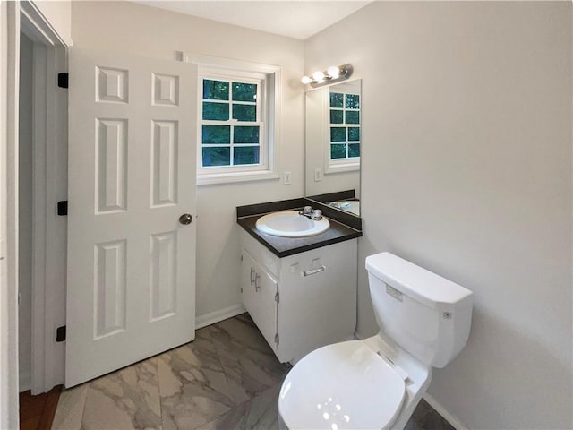 bathroom with baseboards, toilet, marble finish floor, and vanity