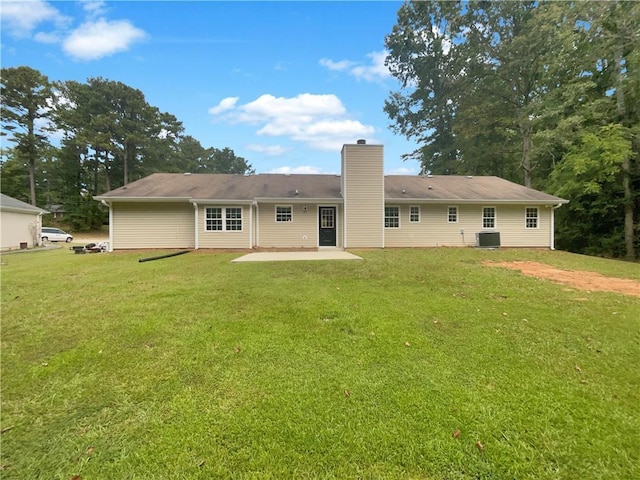 rear view of property featuring a patio, a yard, and a chimney