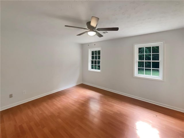 unfurnished room featuring visible vents, wood finished floors, baseboards, and ceiling fan