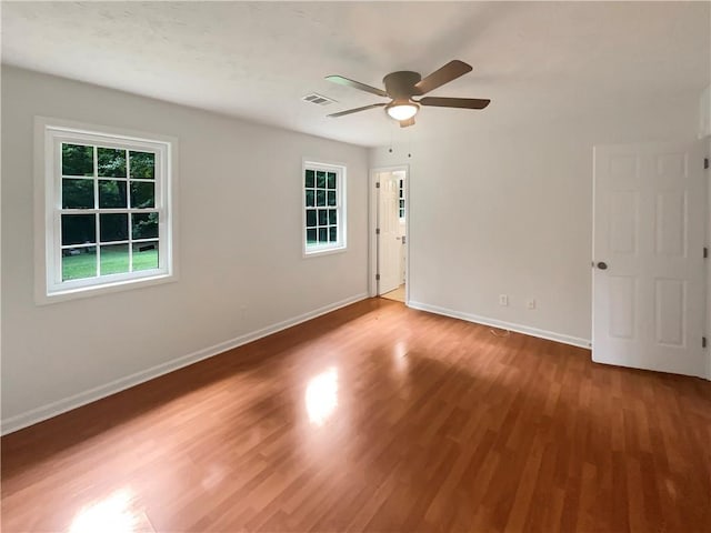 unfurnished room with visible vents, baseboards, wood finished floors, and a ceiling fan