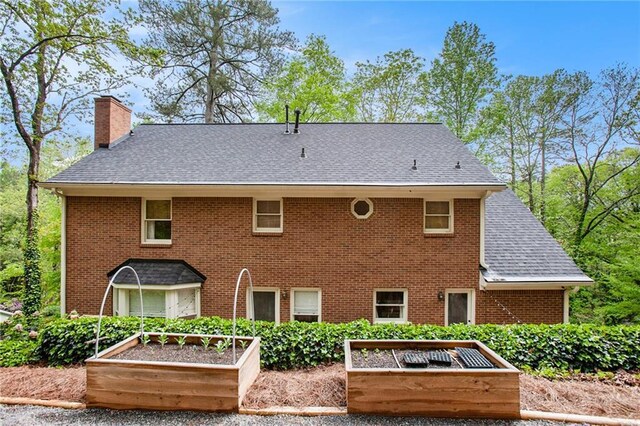 297 Breeze Hill Ln, Canton, GA 30114 - back of property with a vegetable garden, a chimney, and a shingled roof