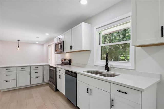 kitchen featuring white cabinets, a sink, light countertops, stainless steel appliances, and a peninsula