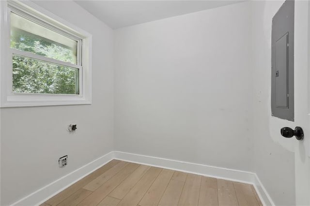 clothes washing area featuring baseboards, light wood-style flooring, and electric panel