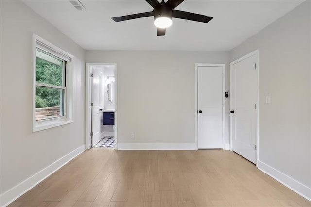 unfurnished bedroom with a ceiling fan, visible vents, baseboards, light wood-style floors, and ensuite bath