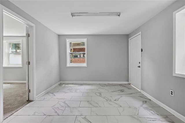 unfurnished room featuring baseboards and marble finish floor