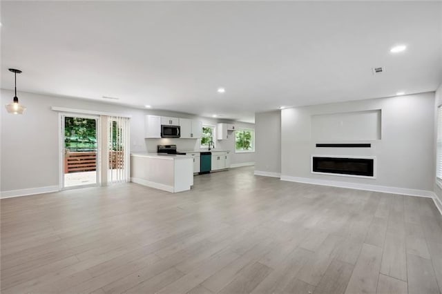 unfurnished living room featuring recessed lighting, plenty of natural light, and light wood-style flooring