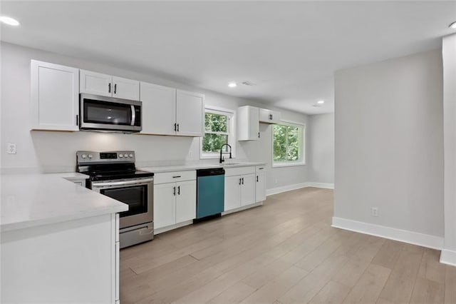 kitchen featuring light countertops, white cabinetry, baseboards, and appliances with stainless steel finishes