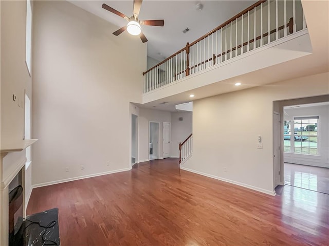 unfurnished living room with a fireplace, stairway, baseboards, and wood finished floors