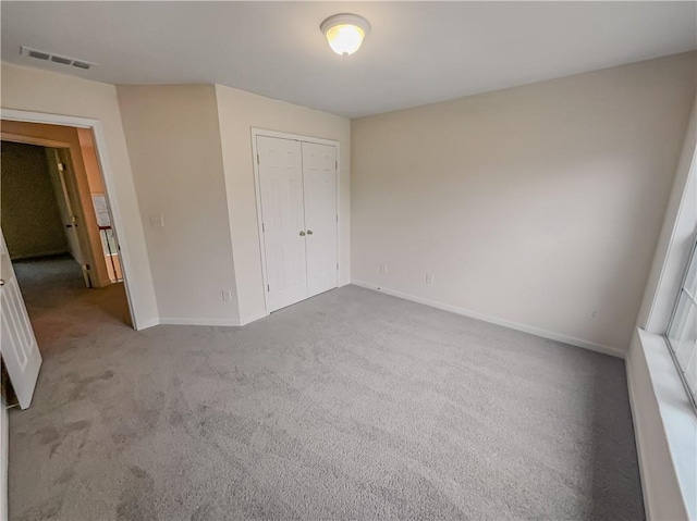 unfurnished bedroom with a closet, visible vents, light carpet, and baseboards