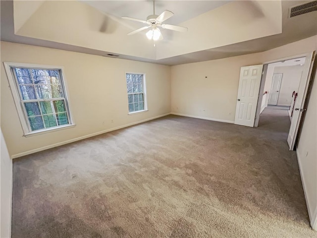 unfurnished bedroom featuring baseboards, visible vents, a raised ceiling, and dark colored carpet