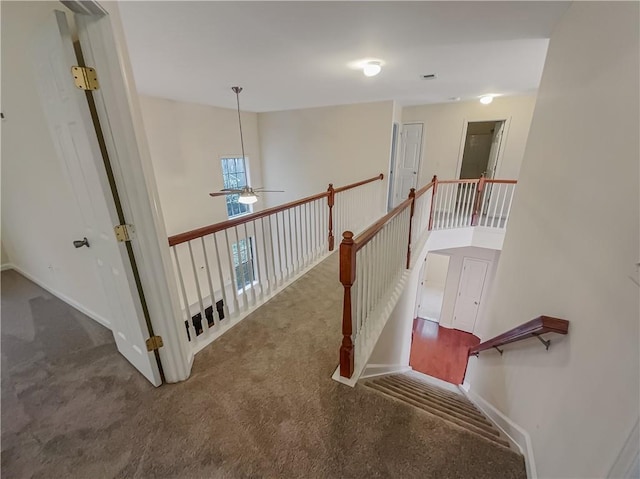 staircase with ceiling fan and carpet