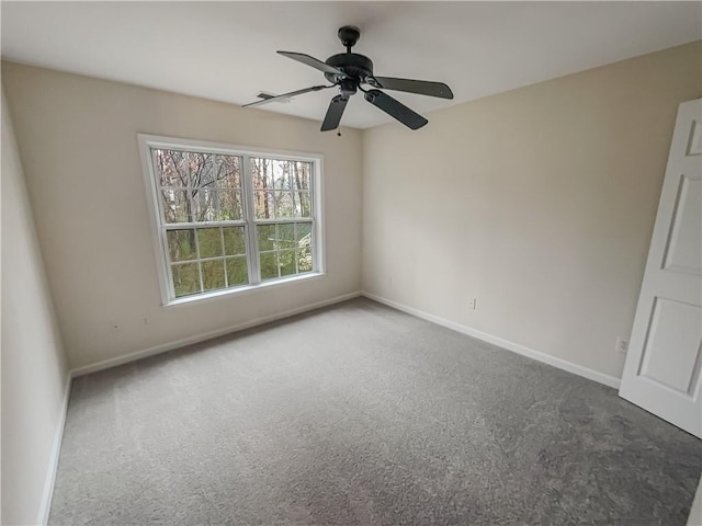 carpeted spare room featuring a ceiling fan and baseboards