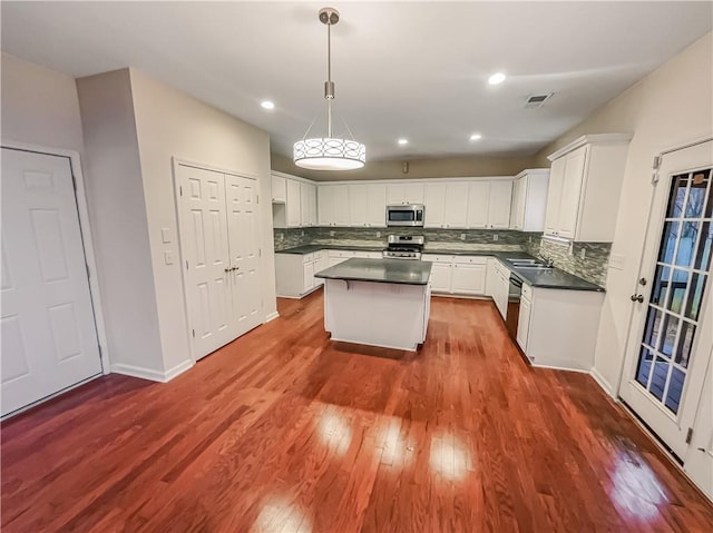 kitchen featuring dark countertops, appliances with stainless steel finishes, white cabinets, and a center island