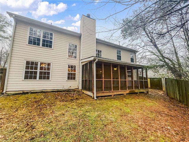 back of property with a sunroom, a fenced backyard, a chimney, and a yard