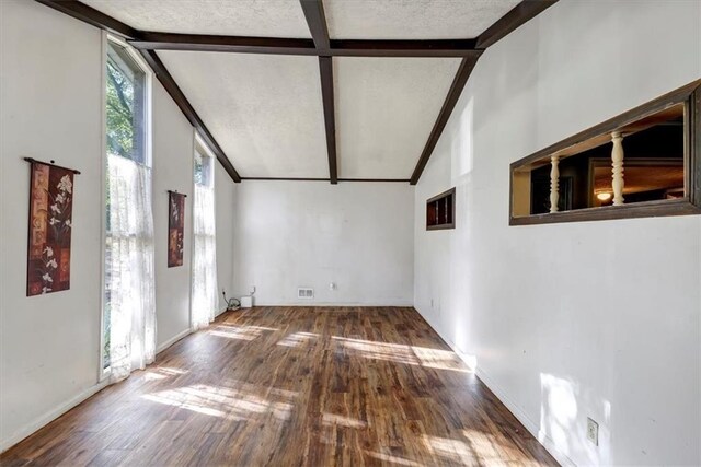 empty room featuring beamed ceiling, hardwood / wood-style floors, and high vaulted ceiling