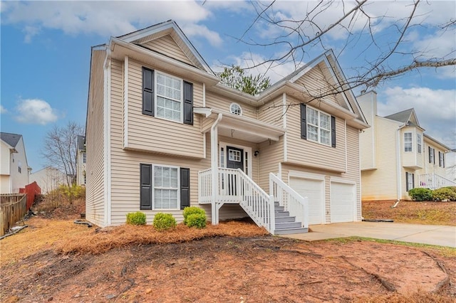 split foyer home with concrete driveway, fence, and an attached garage