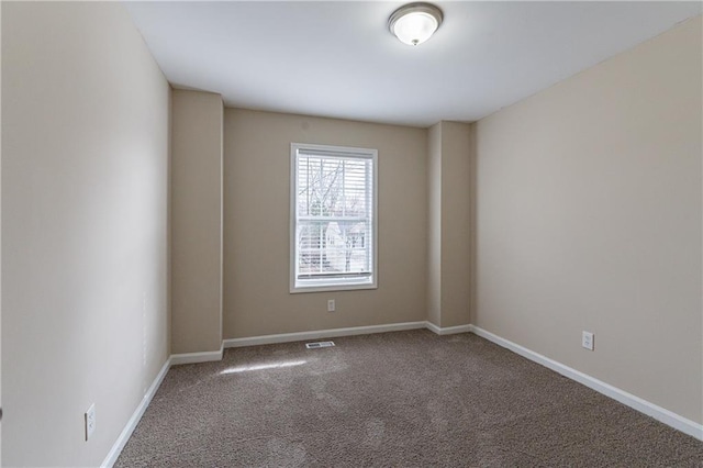 carpeted spare room featuring visible vents and baseboards