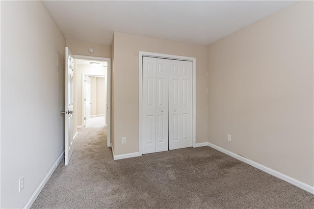 unfurnished bedroom featuring baseboards, a closet, and light colored carpet