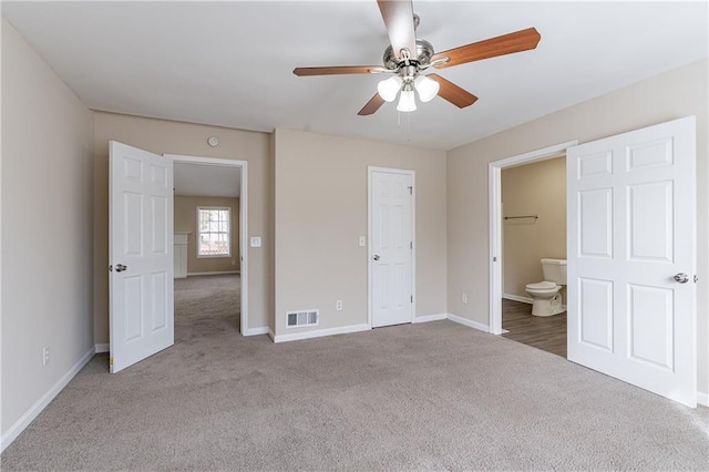 unfurnished bedroom featuring visible vents, ensuite bathroom, carpet flooring, ceiling fan, and baseboards