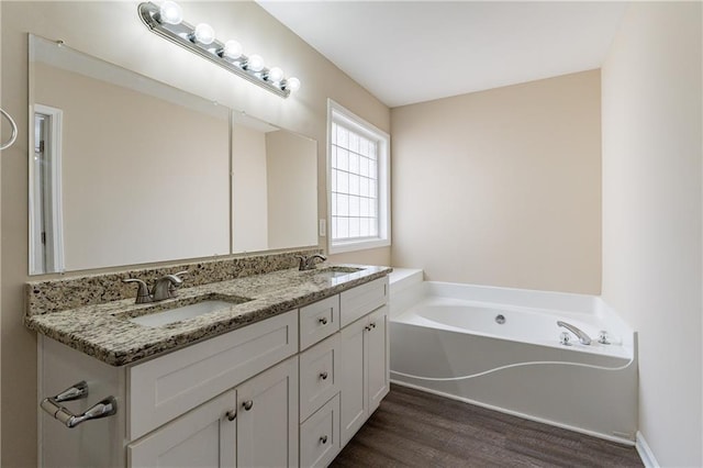 full bathroom featuring double vanity, a garden tub, a sink, and wood finished floors