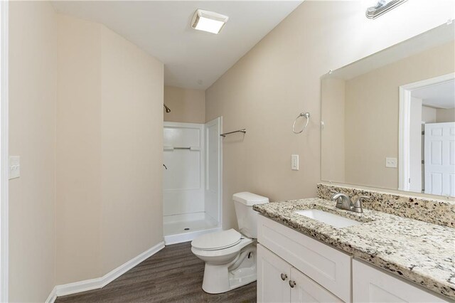 full bath featuring toilet, a stall shower, vanity, wood finished floors, and baseboards