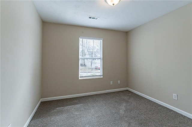 empty room with carpet flooring, visible vents, and baseboards