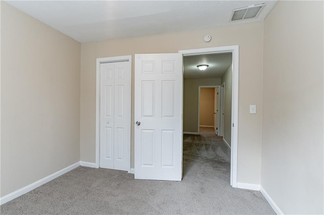 unfurnished bedroom featuring baseboards, visible vents, a closet, and light colored carpet