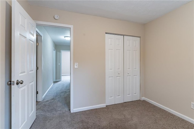 unfurnished bedroom with carpet, a closet, and baseboards