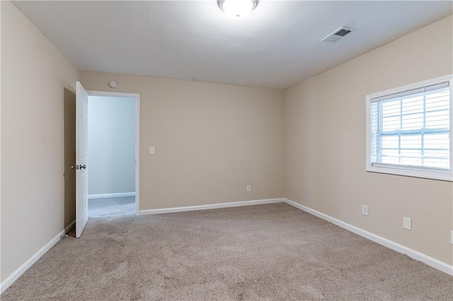 empty room with baseboards, visible vents, and light colored carpet