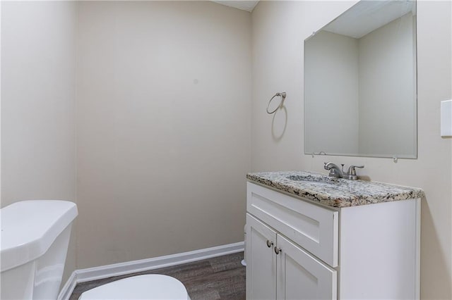 bathroom with toilet, baseboards, wood finished floors, and vanity