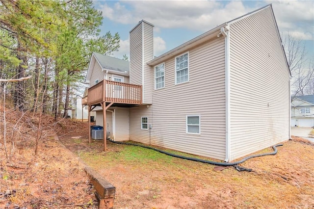 rear view of property with a chimney, a wooden deck, and central air condition unit