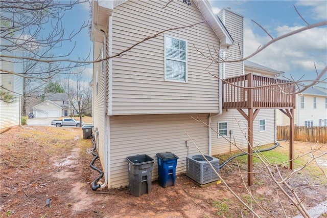 rear view of house featuring fence and central AC