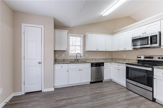 kitchen featuring white cabinets, light stone counters, stainless steel appliances, and a sink