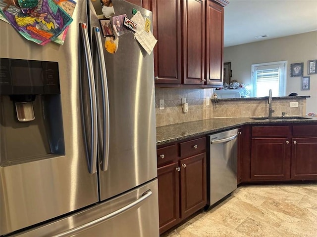 kitchen featuring sink, backsplash, stainless steel appliances, and dark stone countertops