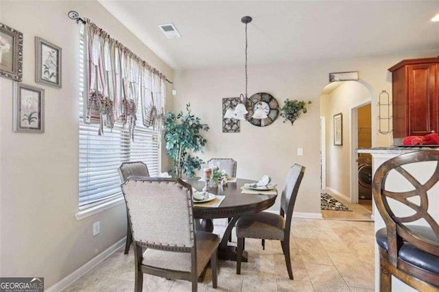 dining room featuring washer / dryer, an inviting chandelier, and light tile patterned floors