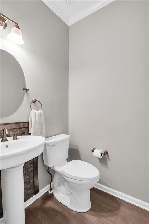 5990 Eagle Tiff Ln, Sugar Hill, GA 30518 - half bathroom featuring wood finished floors, ornamental molding, and backsplash