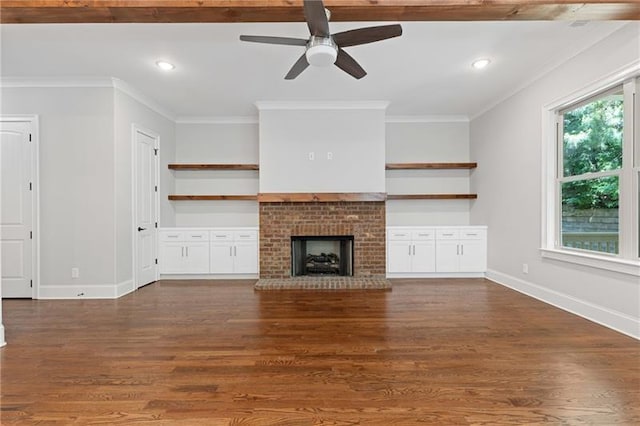 unfurnished living room with crown molding, a brick fireplace, dark wood-type flooring, and ceiling fan