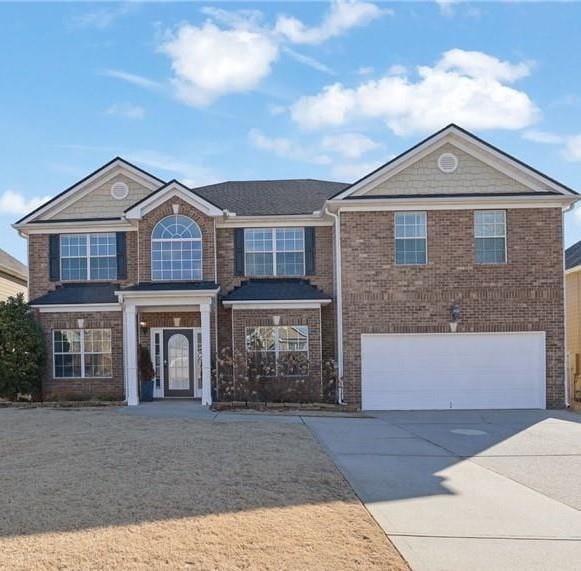 traditional-style home featuring driveway, brick siding, and an attached garage