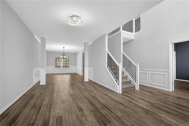 unfurnished living room featuring dark hardwood / wood-style flooring, ornamental molding, and an inviting chandelier