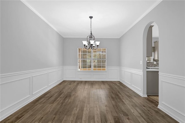 unfurnished dining area featuring dark wood-type flooring, crown molding, and a notable chandelier