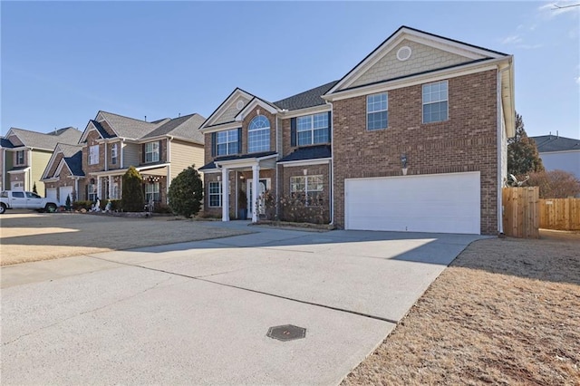 traditional-style home featuring brick siding, fence, a garage, a residential view, and driveway