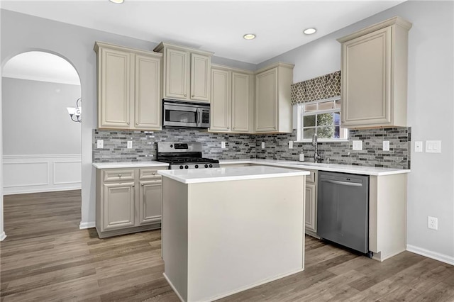 kitchen with light hardwood / wood-style flooring, cream cabinets, a kitchen island, and appliances with stainless steel finishes