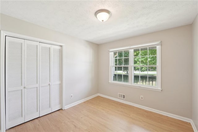 3388 Hamilton Mill Rd, Buford, GA 30519 - unfurnished bedroom with light wood finished floors, baseboards, a closet, and a textured ceiling