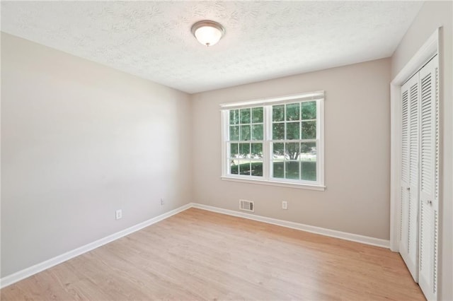 3388 Hamilton Mill Rd, Buford, GA 30519 - unfurnished bedroom featuring light wood-style floors, baseboards, a closet, and a textured ceiling