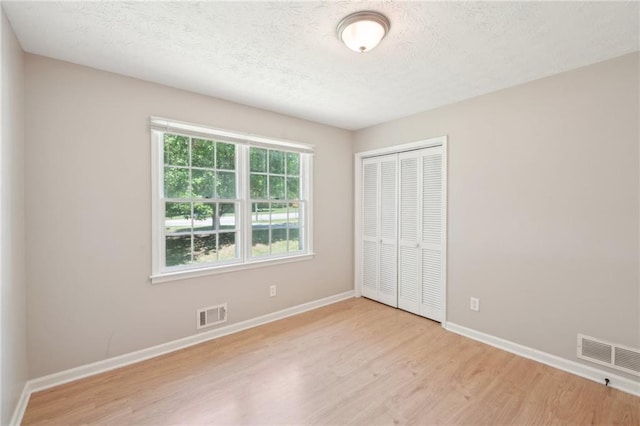 3388 Hamilton Mill Rd, Buford, GA 30519 - unfurnished bedroom with wood finished floors, a closet, baseboards, and a textured ceiling