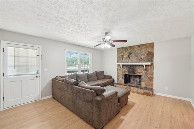 3388 Hamilton Mill Rd, Buford, GA 30519 - living room with light wood-style flooring, a textured ceiling, a ceiling fan, baseboards, and a stone fireplace